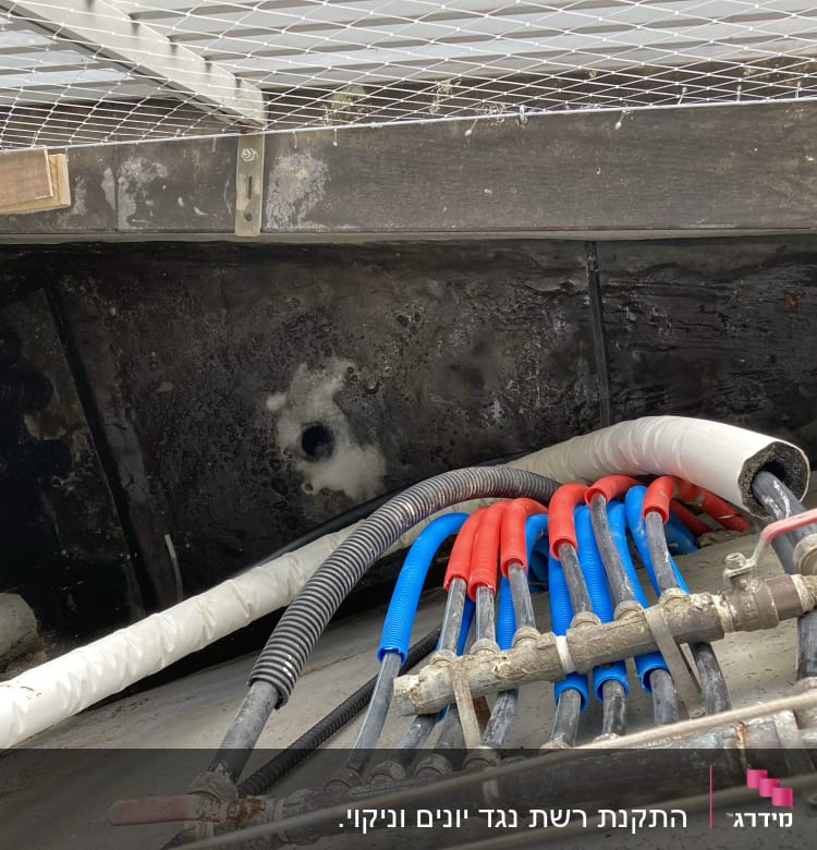 צינורות צבעוניים מתחת לרשת מתכת על קיר